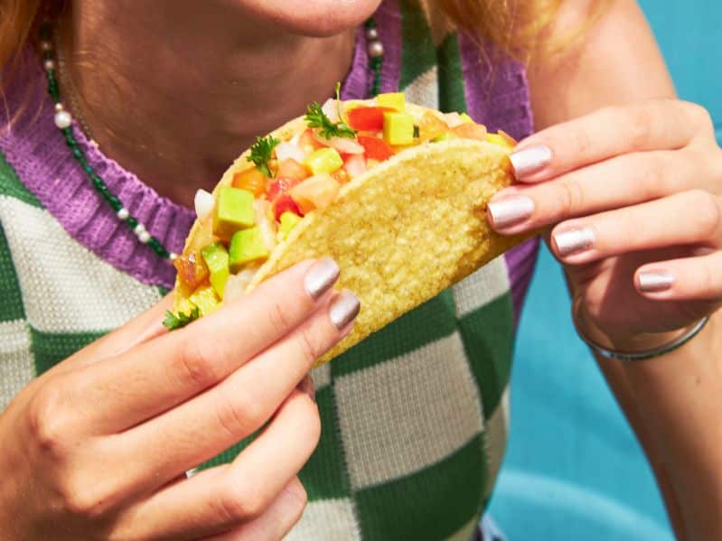 close up of a woman holding a street taco