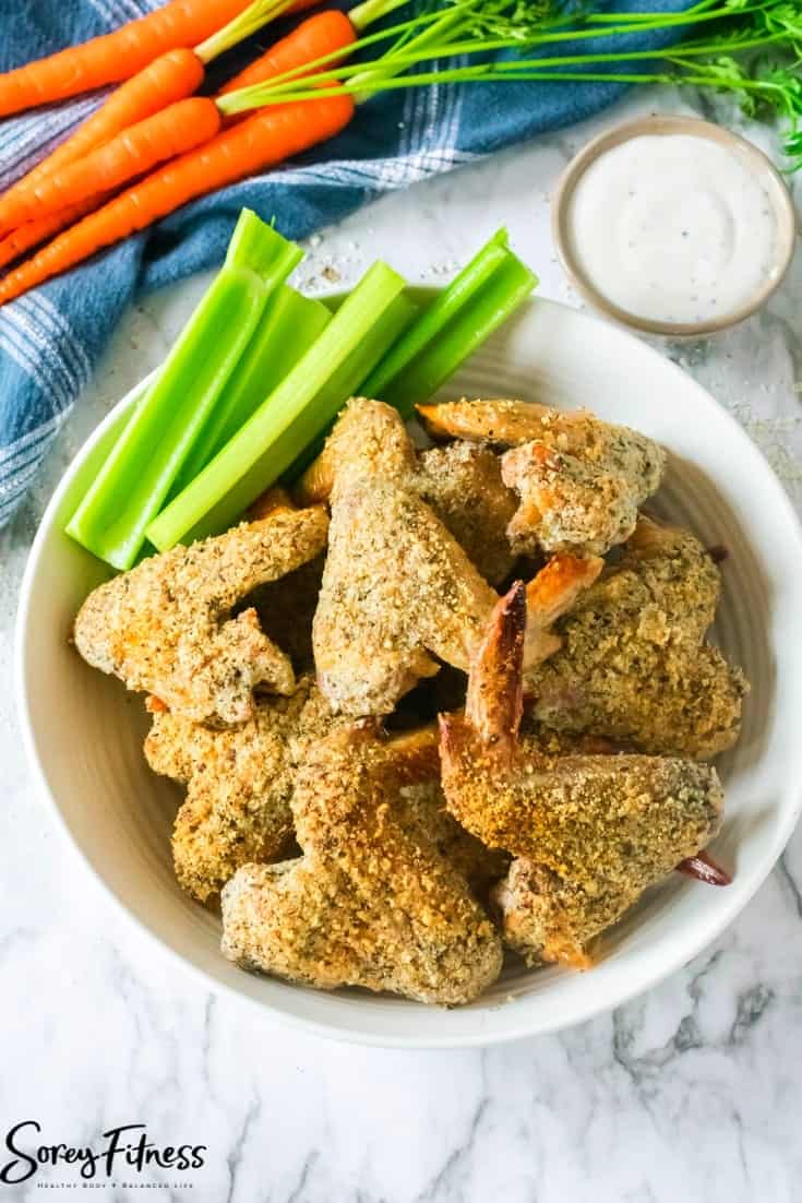 keto chicken wings in a bowl with celery and carrots around it