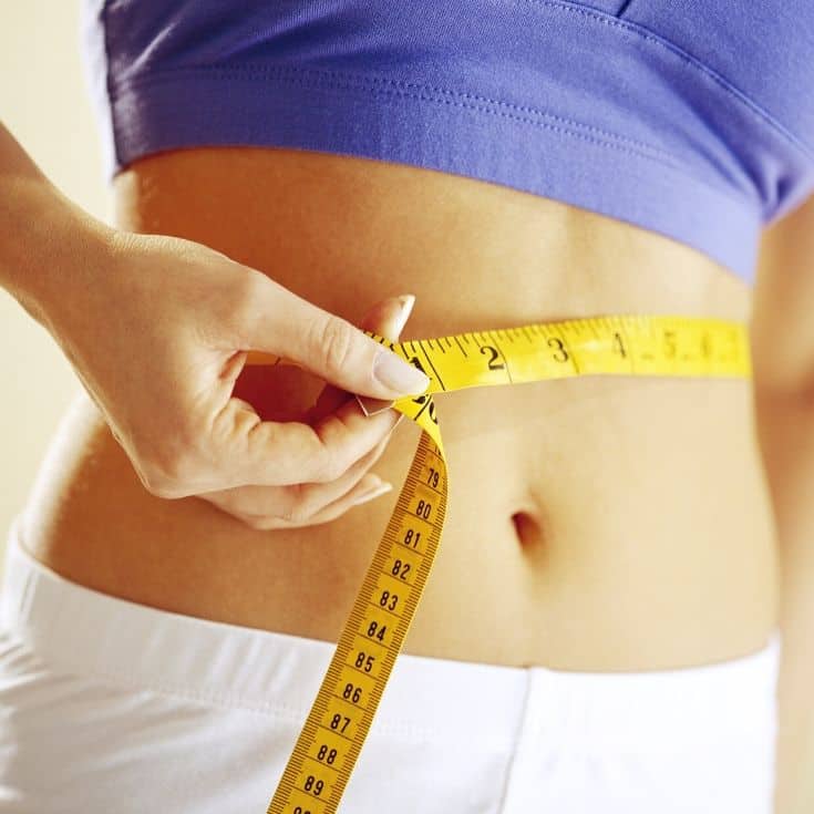 a woman measuring her waist