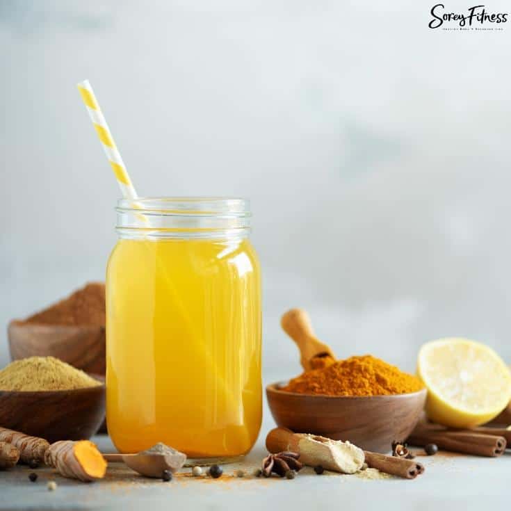 lemon cayenne ginger water in a mason jar with a straw surrounded by its ingredients