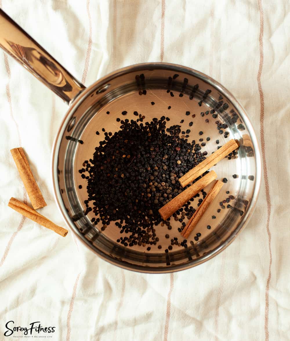 saucepan with elderberries and cinnamon sticks in it