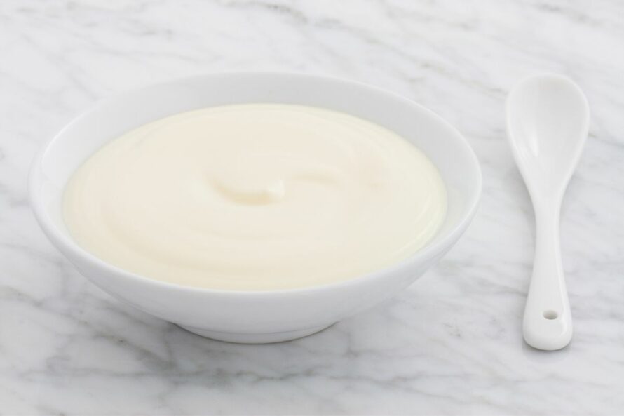 bowl of plain yogurt with a spoon beside it