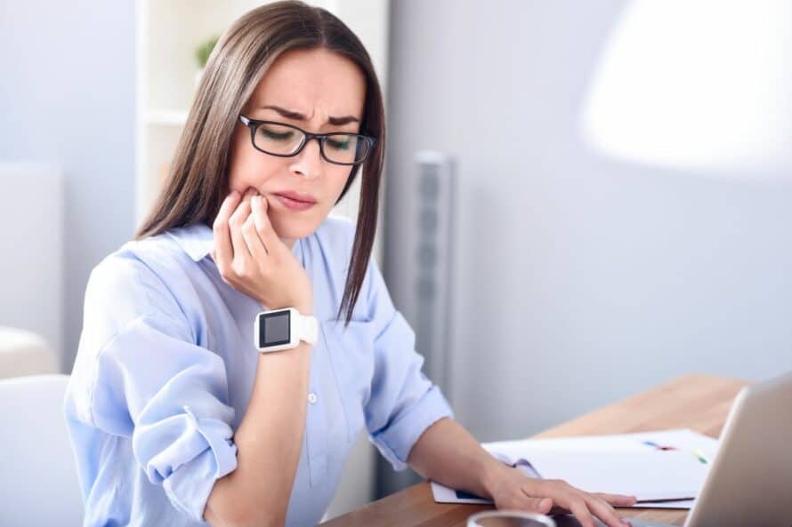 woman with a tooth ache working at her computer