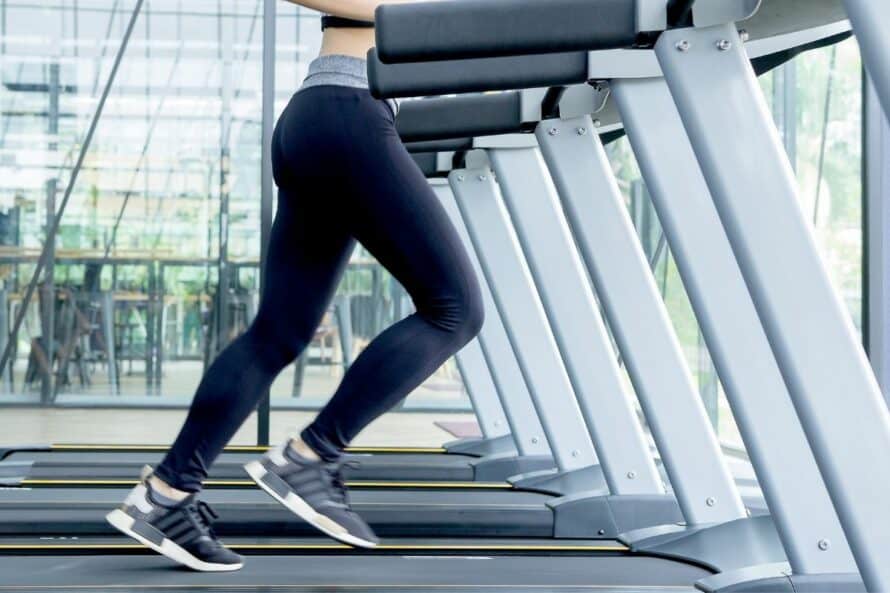 close up of a woman walking on a treadmill in a gym