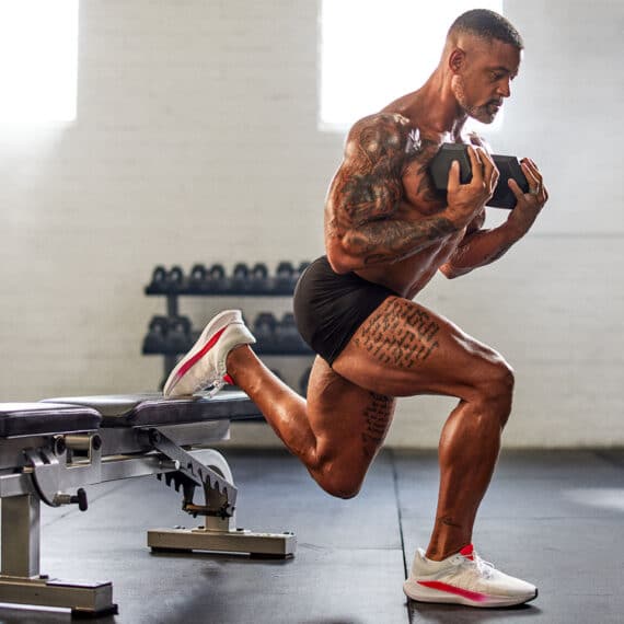 shaun t doing a lunge with a weight bench and weight