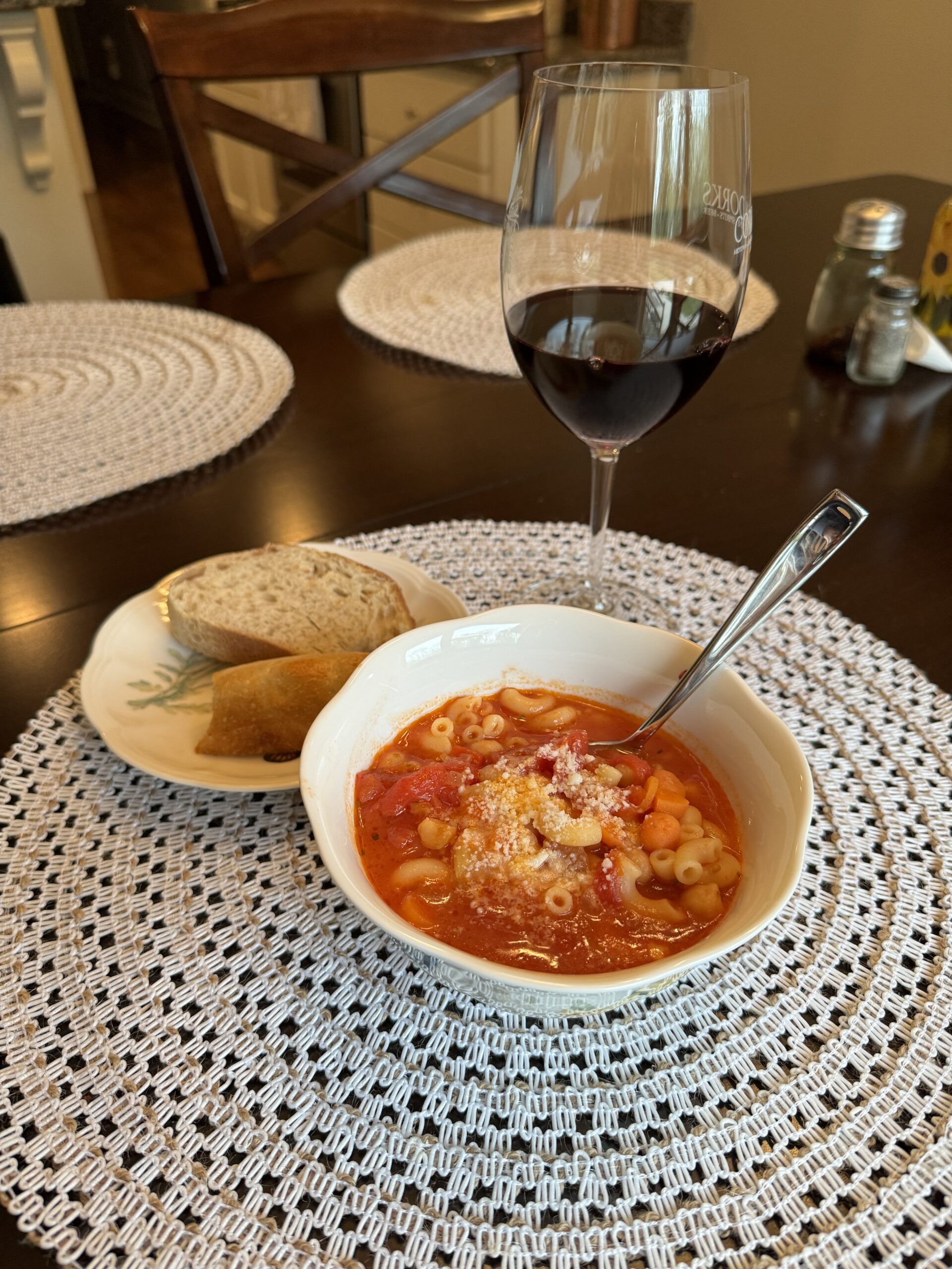 bowl of Chickpea and Pasta Soup served with sourdough bread and a glass of red wine