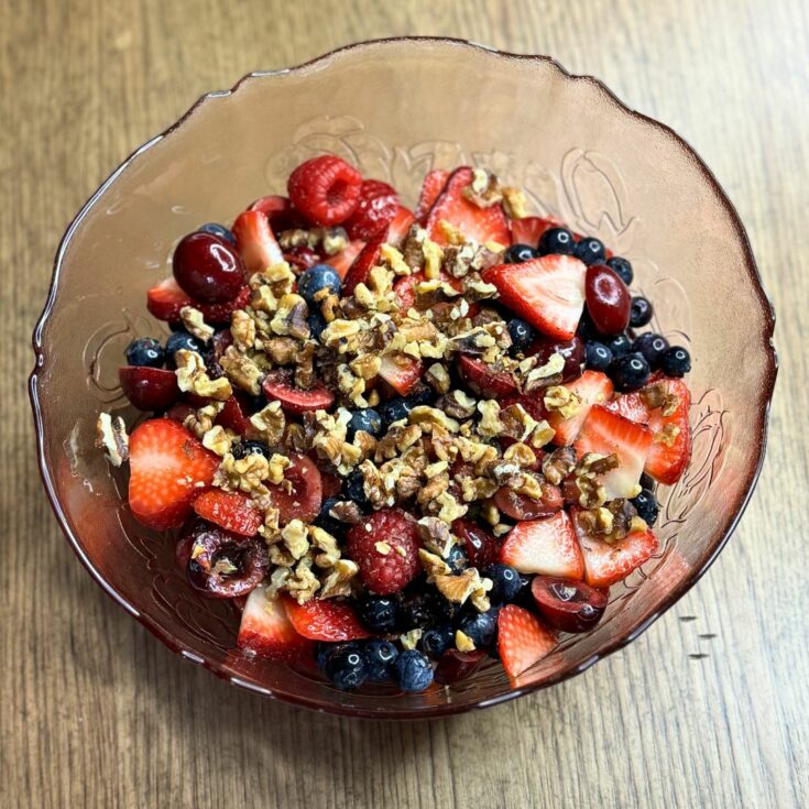 Healthy fruit salad with berries, cherries and walnuts in a serving bowl
