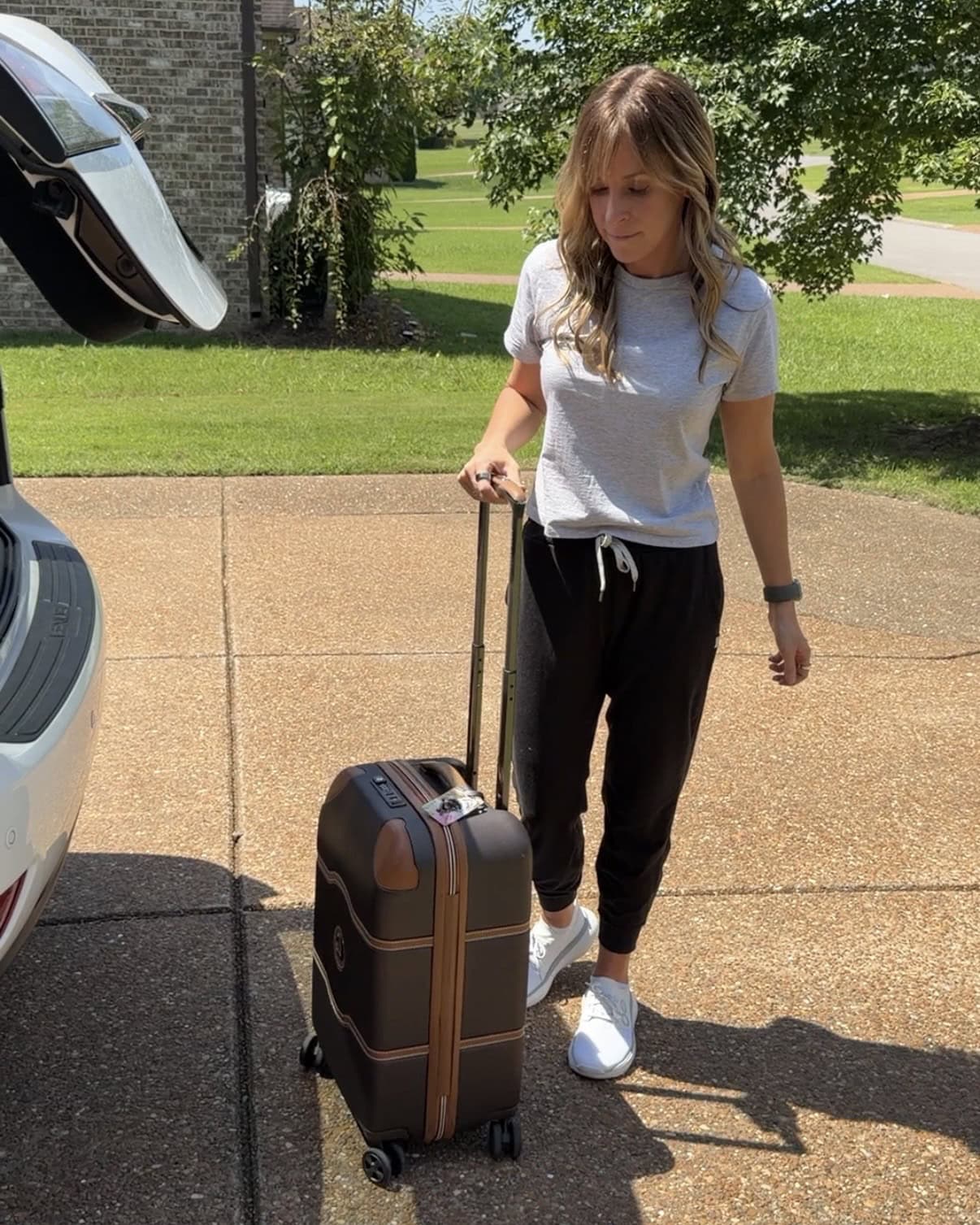 Kalee with her suitcase traveling in her OOFOS